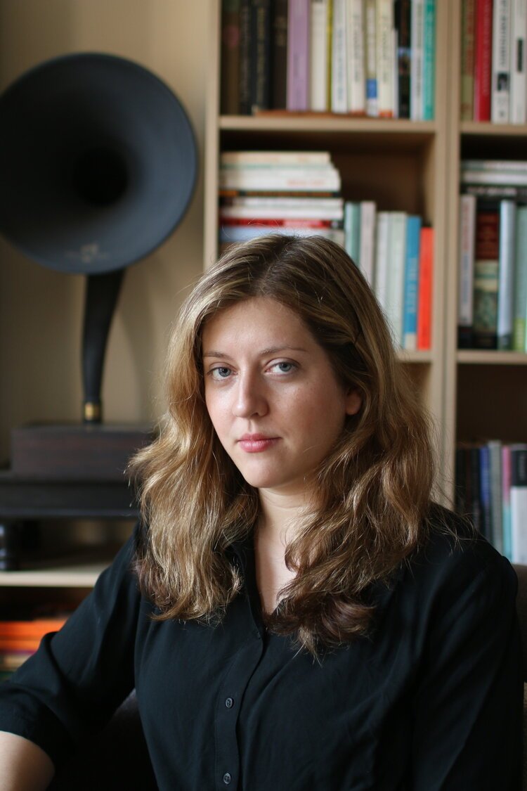 Professor Skarpelis against a background of a bookshelf, wearing a black shirt