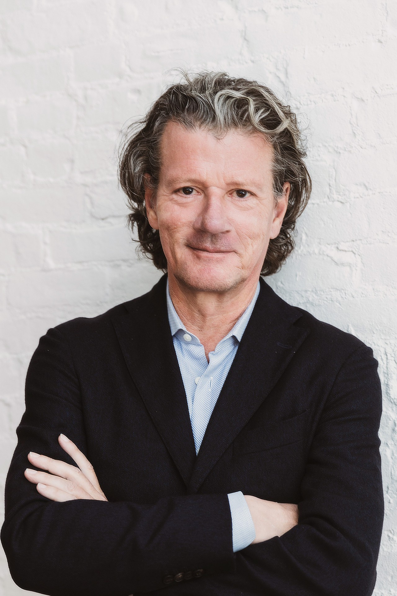 Professor Wimmer wearing a black coat with a blue shirt standing against a white background