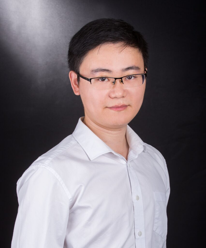 Professor Zhang against a black background wearing a white shirt and glasses